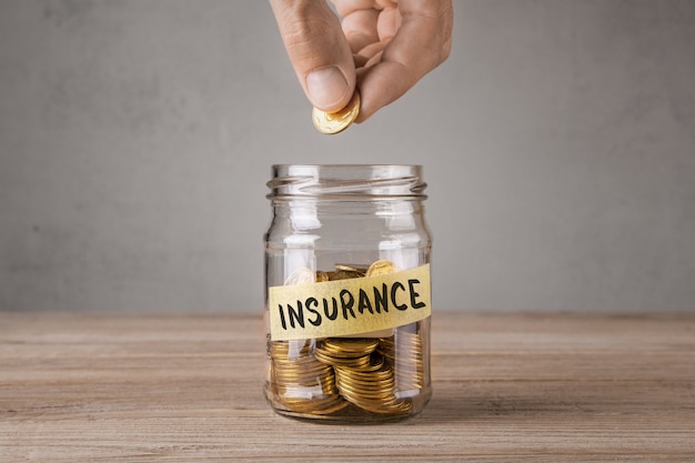 Insurance. Glass jar with coins and an inscription insurance. Man holds  coin in his hand