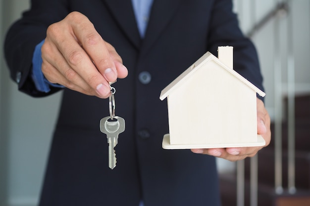 Insurance salesmen hold house models and keys