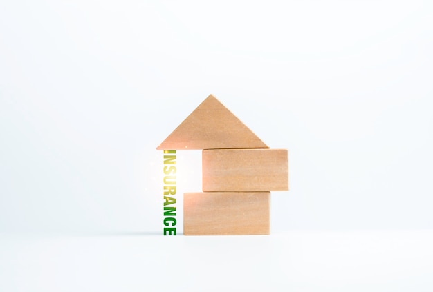 Insurance, word supporting under the wooden block stack, house shape on white background, minimal style. Property, family insurance protection concept.