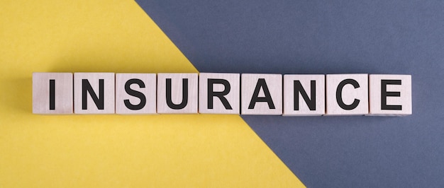 Photo insurance word written in wooden cubes on yellow and gray desk