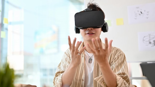 an intelligent asian male wearing vr glasses trying modern virtual experience