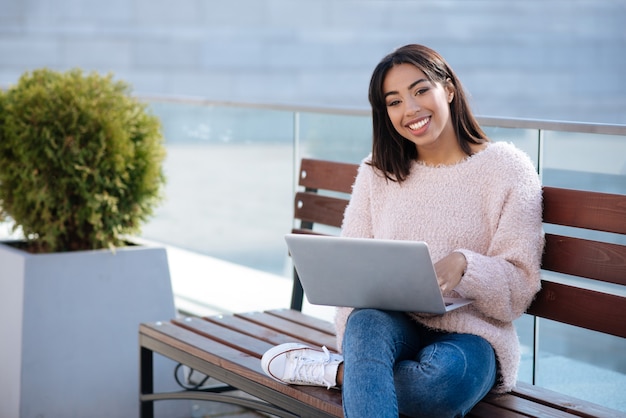 Intelligent dedicated active girl using her laptop for fulfilling everyday tasks and working from any place she liking