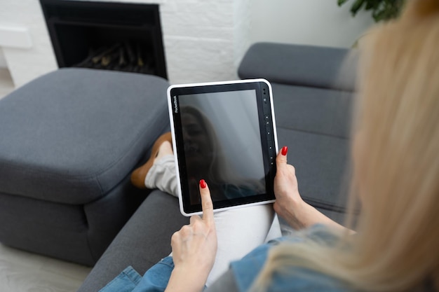 Intelligent home concept. Young woman using smart home application on a tablet.