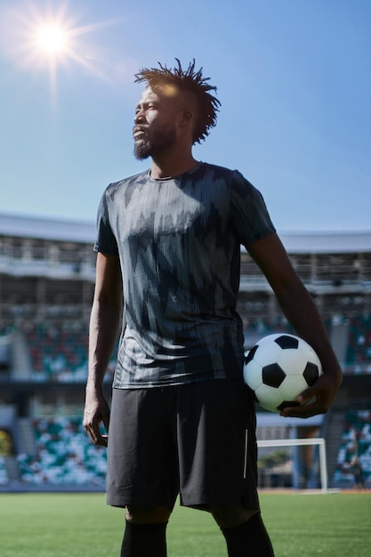 スタジアムでボールを握っているサッカー選手の強烈な肖像画