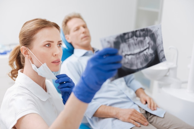Intent zorgvuldig getrainde tandarts observeert de scan van de kaaklijn van haar patiënten en werkt aan het ontwikkelen van de diagnose- en behandelingsstrategieën