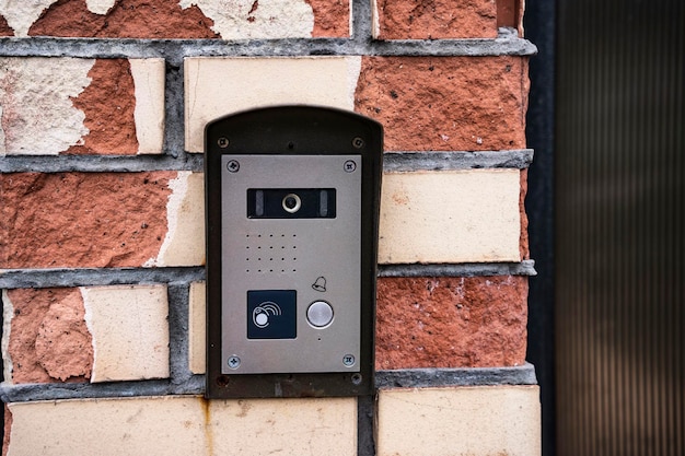 Intercom panel with a video camera on the brick fence of private house