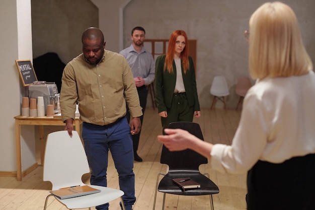 Foto interculturele patiënten van psycholoog die vóór de sessie hun plaats in de grote kamer innemen