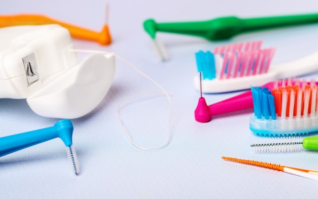 Interdental toothbrushes, dental floss, and toothbrushes on blue background