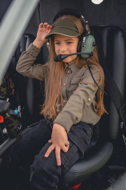 Interested preteen girl in headset sitting on pilot seat in helicopter