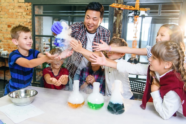 Interested schoolchildren study the chemical reactions of exchange on the example of colored liquids in glass flasks.