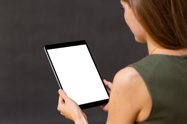 Interested woman holding tablet with white screen in portrait orientation