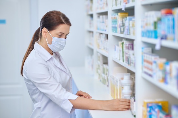 Farmacista donna interessata che esamina i medicinali sugli scaffali