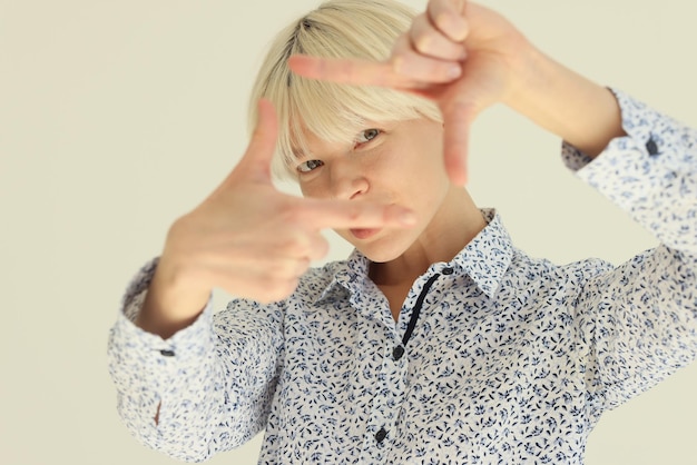 Interested woman puts fingers in shape of camera screen