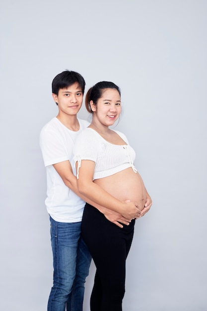 재미있는 아시아 부부, 행복한 임신 어머니와 아버지는 흰색 표면에 고립, 국제 가족의 날