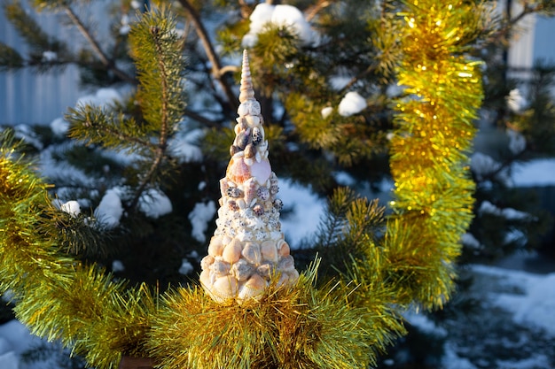 An interesting decorative Christmas tree stands on the street near a large pine tree