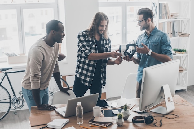 Interesting discussion.  Group of young business people working and communicating together while standing in creative office