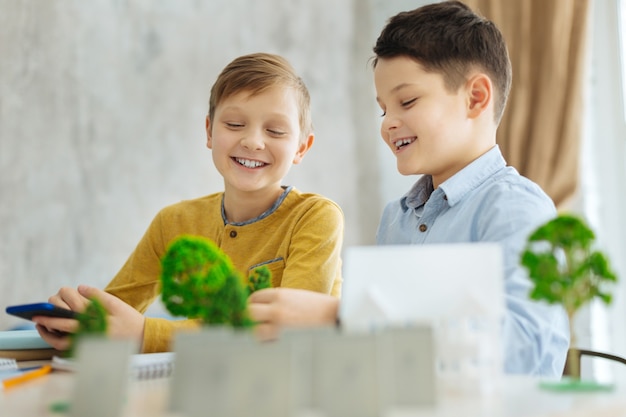 Interesting home assignment. Two upbeat pre-teen boys sitting at the table and creating the model of the miniature neighborhood for their ecology project together