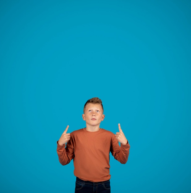 Photo interesting offer little boy pointing up at copy space above his head