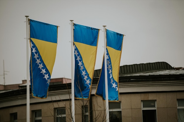 Interesting shot of and three waving flags of Bosnia and Herzegovina in front of a building