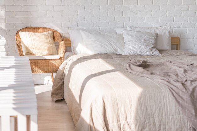 Foto interieur, slaapkamer in zachte lichte kleuren met tweepersoonsbed, sprei. kussens.