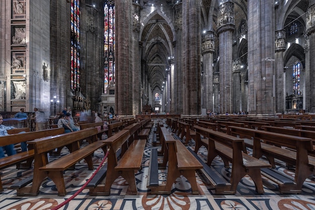 Interieur van de Duomo kathedraal met marmeren zuilen, glas-in-loodramen en houten banken Milaan Italië