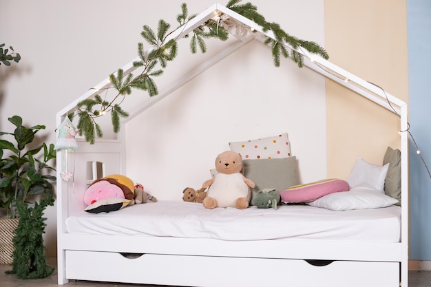 Interieur van een kinderkamer met speelgoed Scandinavisch ontwerp van een kinderkamer met een houten bed in de vorm van huisontwerpersmeubilair