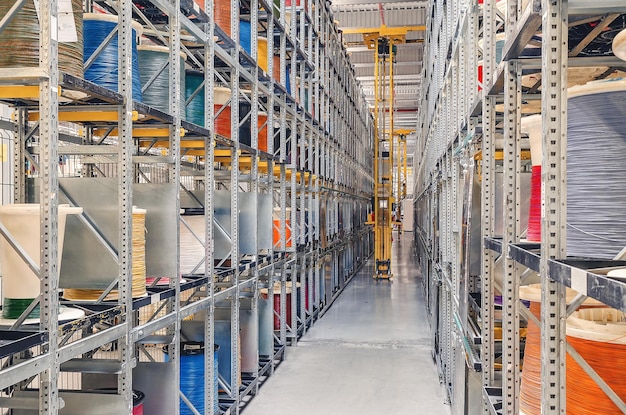 Interieur van een modern opslagmagazijn met spoelen van gekleurde kabel op metalen planken Forklift