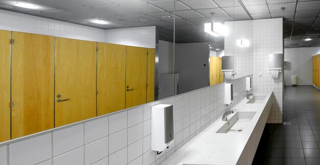 Foto interieur van een openbaar toilet met wastafels, kranen en toiletcabines