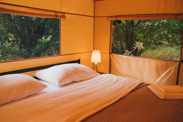 Interieur van gezellige open glamping-tent met licht binnen tijdens de schemering luxe kampeertent voor buiten zomervakantie en vakantie lifestyle-concept
