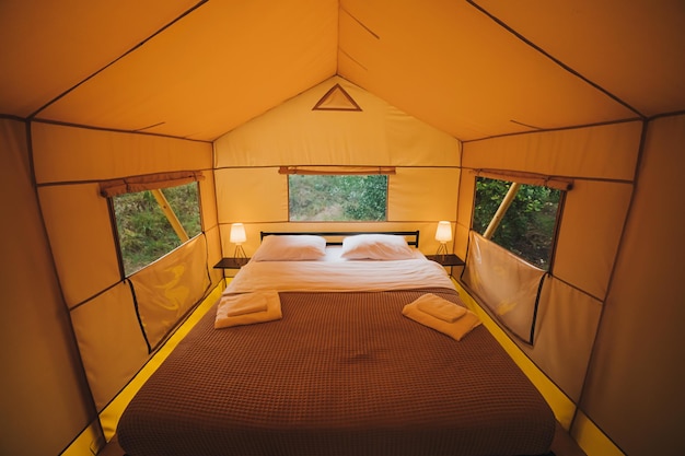 Interieur van gezellige open glamping-tent met licht binnen tijdens de schemering Luxe kampeertent voor buiten zomervakantie en vakantie Lifestyle-concept