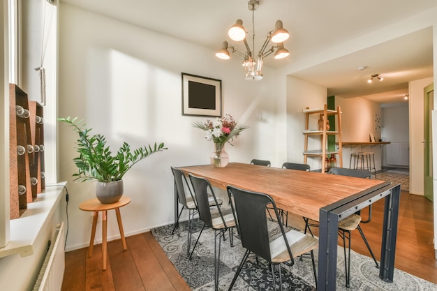 Interieur van het eetgedeelte met een houten tafelblad onder een lichte kroonluchter in een modern huis