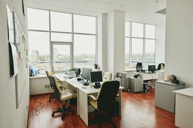 Interieur van modern groot kantoor in modern centrum met bureaus, computerschermen, witte lederen fauteuils en andere dingen