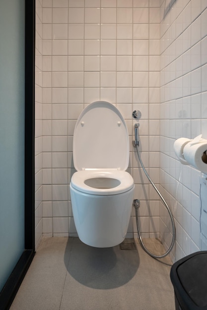 Interieur van modern toilet met bidetspray en papieren zakdoekje op keramische wand