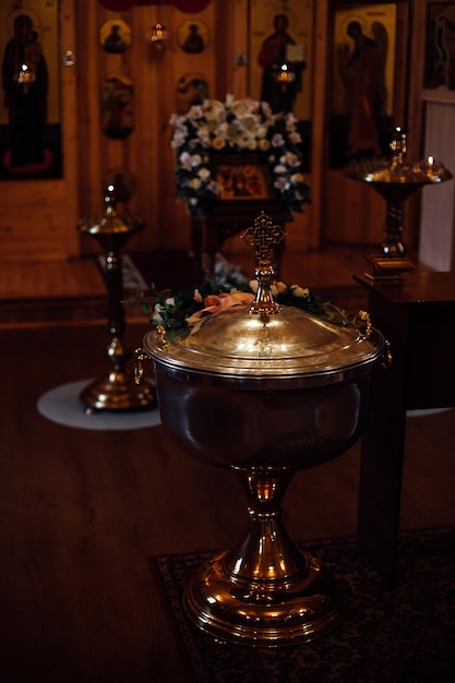 Interieur van traditionele orthodoxe kerk met glanzend lettertype met kruis lessenaar altaar versierd met bloemen iconostase