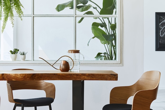 Interieurontwerp van eetkamer met stijlvolle ambachtelijke houten familietafel, stoelen, veel planten, raam, kaart en elegante accessoires in modern interieur.