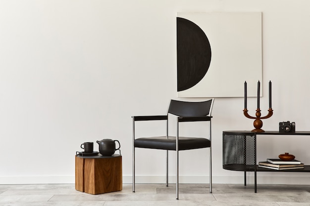 Interieurontwerp van moderne woonkamer met zwarte stijlvolle commode, stoel, kunstschilderijen, lamp, boek, kandelaar, decoraties en elegante accessoires in huisdecor.