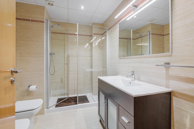 Interior of a bathroom in light tones with shower cabin toilet and sink