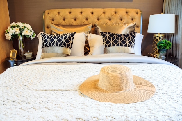 An interior bedroom design with lady straw hat on luxury bed.