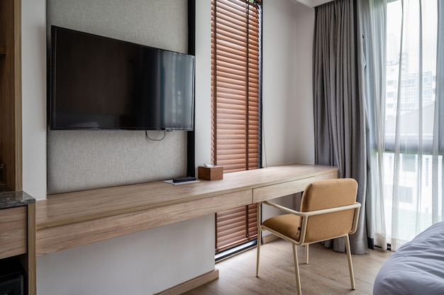 Photo interior of bedroom designed in cozy wood style. wooden desk and chair with sunlight through curtain