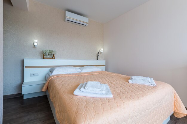 Interior of a bedroom with white walls and a large double bed\
with a white blanket in the hotel