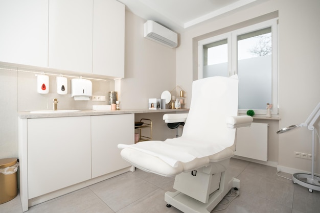 Interior of bright white beauty parlor with specialized couch\
for cosmetic procedures and professional equipment with furniture.\
cosmetology, massage, dermatology, medical, beauty parlor\
concept.