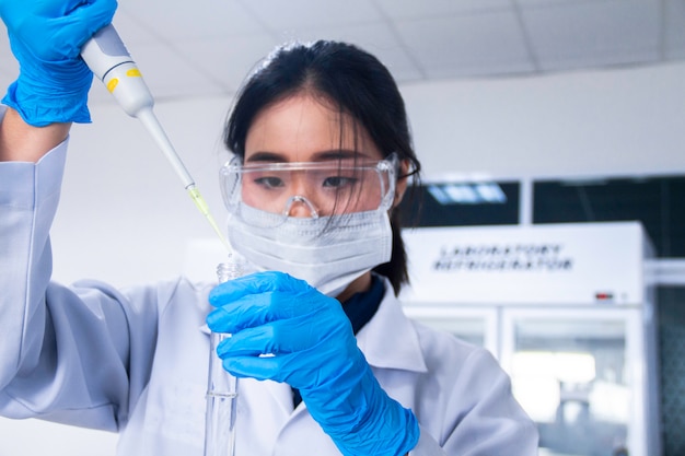 Foto interno del laboratorio bianco pulito moderno di chimica o di chimica. scienziato che lavora in un laboratorio con micro pipetta e provette. concetto di laboratorio con chimico donna asiatica. messa a fuoco selettiva.