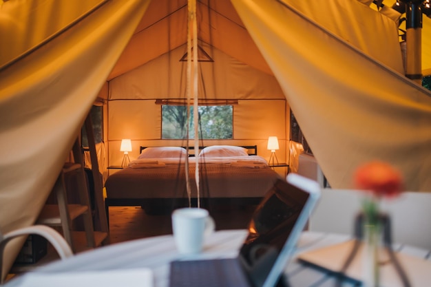 Interno di un'accogliente tenda glamping aperta con luce interna durante il tramonto tenda da campeggio di lusso per vacanze estive all'aperto e vacanze concetto di stile di vita