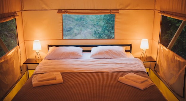 Interno di un'accogliente tenda glamping aperta con luce interna durante il tramonto tenda da campeggio di lusso per vacanze estive all'aperto e vacanze concetto di stile di vita