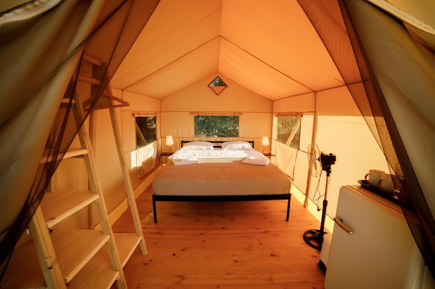 Interior of Cozy open glamping tent with light inside during sunset Luxury camping tent for outdoor summer holiday and vacation Lifestyle concept