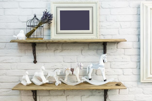 Interior decoration toys White decorative bird near cage and ceramic horses and foto frame in expensive interior