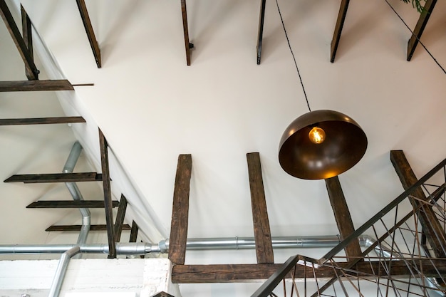 カフェのインテリア デザイン レストランの天井の眺め デザイナー天井の装飾的な木製の梁 金属製のシャンデリアとランプ 天井に沿った換気パイプ