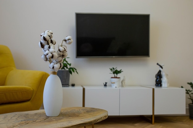 Interior design of a cozy living room with tv armchair coffee\
table and withered flowers in a vase