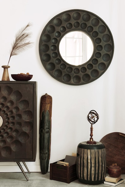 Дизайн интерьера этнической гостиной с современным комодом, круглым зеркалом, декоративной мебелью и личными аксессуарами Шаблон Белая стена
