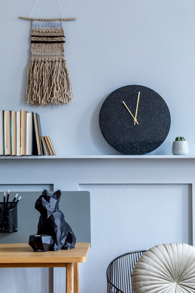 Photo interior design of home office room with wooden desk, armchair, plant, books, black clock and elegant personal accessories in modern home decor.